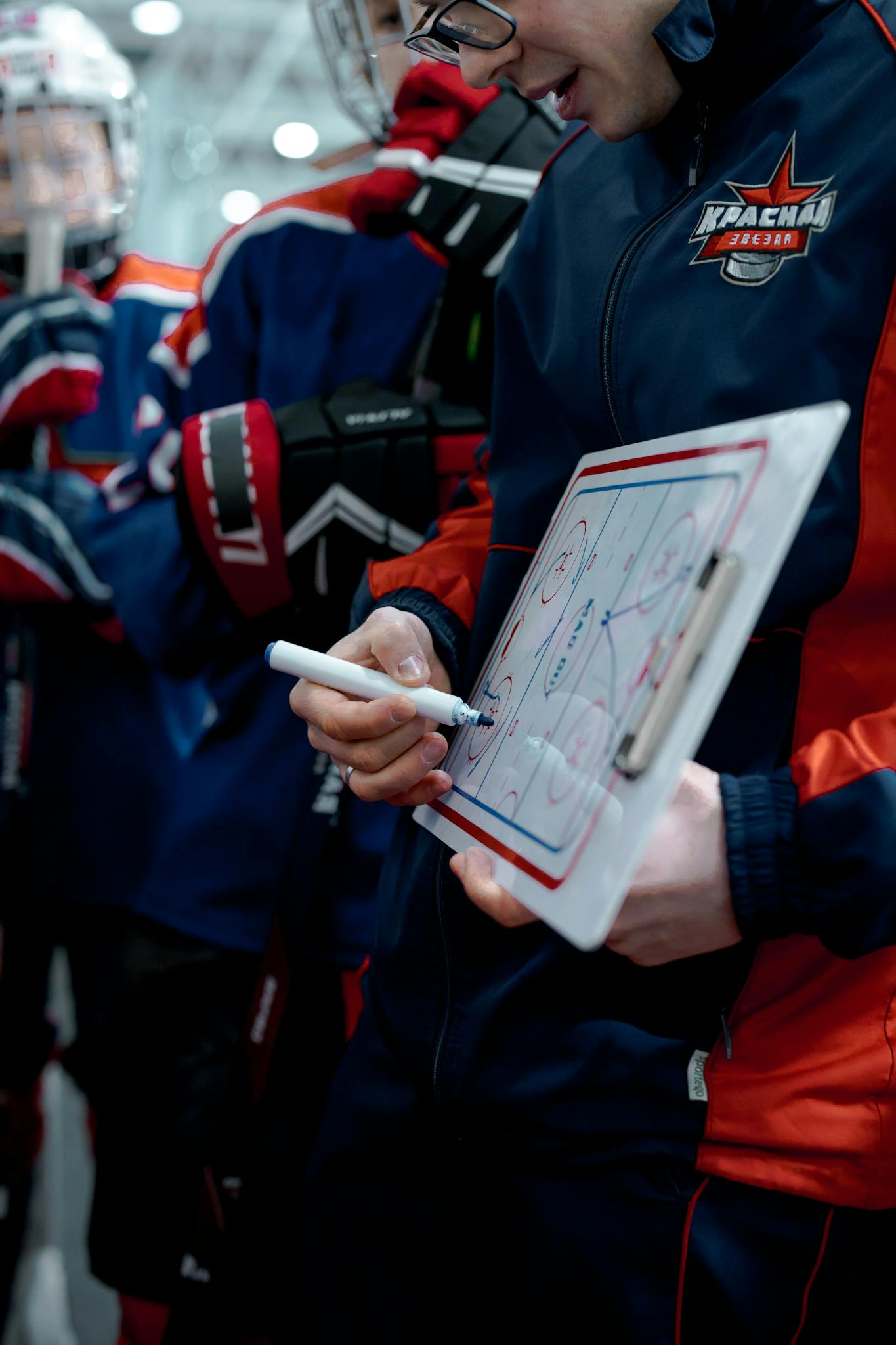 Ice hockey coach explaining strategy to players on a whiteboard.