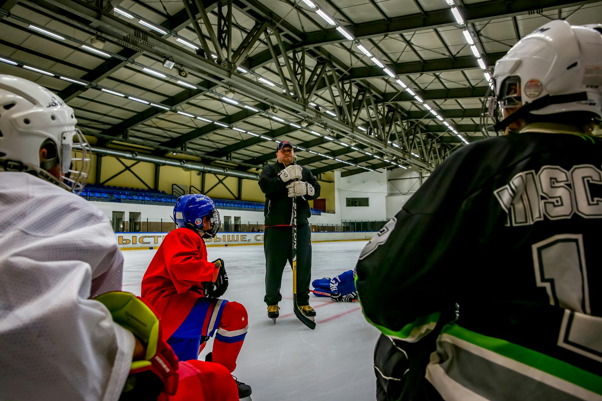 Ice hockey players and coach during a training session in an indoor ice arena.