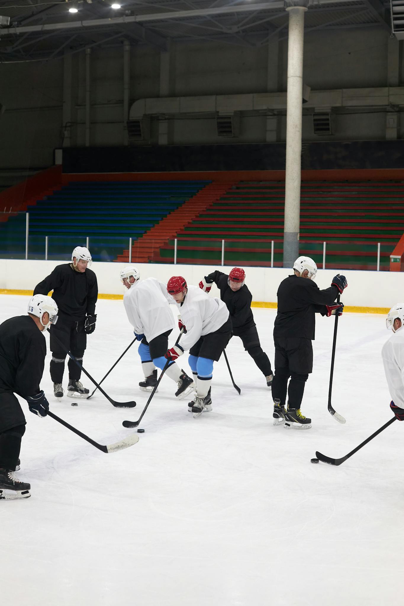 Men playing hockey on an indoor rink, practicing teamwork and skills.